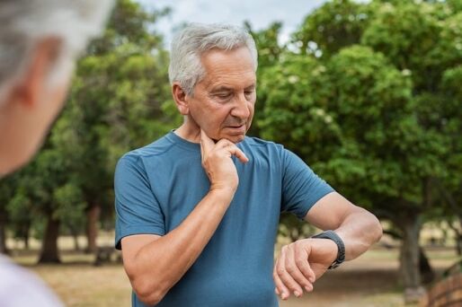 Senior man checking pulse after run.